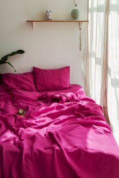 the bed is covered with pink sheets and pillows