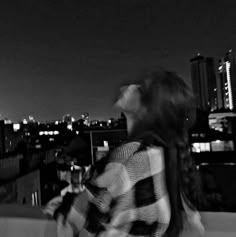 a person standing on top of a roof with a city in the background at night