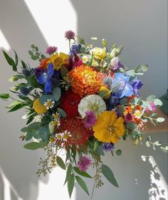 a bouquet of colorful flowers is being held up by someone's hand in the sunlight