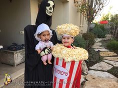 two children in costumes standing next to each other holding popcorn buckets filled with popcorn