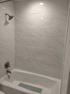 a white bath tub sitting inside of a bathroom next to a wall mounted shower head