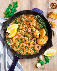 shrimp and grits in a skillet with lemon wedges, parsley and garlic