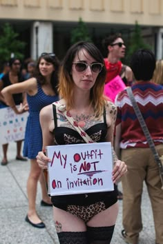 a woman holding a sign that says my outfit is not an invention