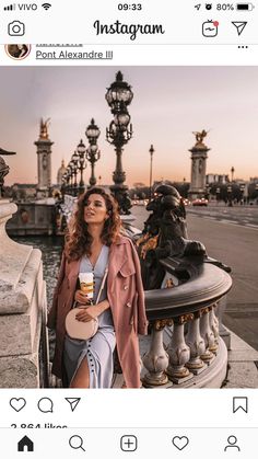 a woman standing on top of a bridge next to a fountain holding a coffee cup