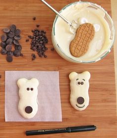 some cookies and chocolate chips are on a wooden table next to a bowl of milk