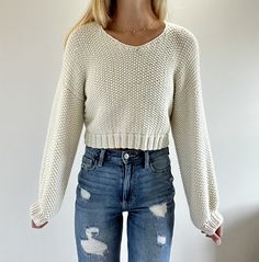 a woman wearing ripped jeans and a sweater