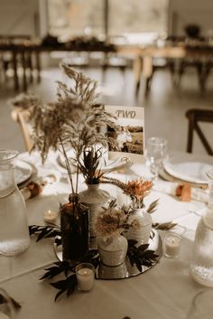 the table is set with vases, candles and cards for guests to write on