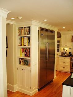 a kitchen with white cabinets and stainless steel refrigerator in the corner next to an island