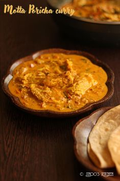 a wooden bowl filled with curry next to tortilla chips on top of a table