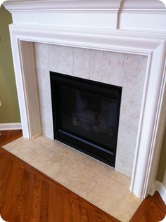 an empty fireplace in a living room with hard wood flooring and white painted mantel