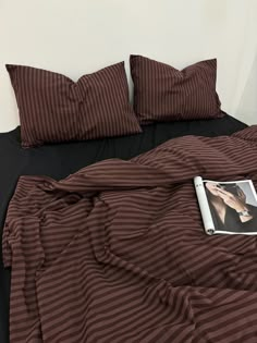 a bed with two pillows and a magazine on it's side next to the covers