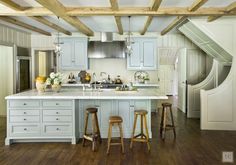 a kitchen with two stools in front of an island and wooden beams on the ceiling