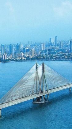 an aerial view of a bridge spanning the width of a large body of water in front of a city