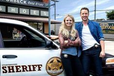 a man and woman standing in front of a sheriff car with their arms around each other