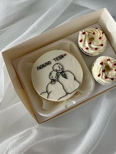 two cupcakes in a box with white frosting