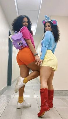 two women in short shorts and boots posing for the camera