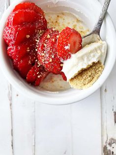 a bowl filled with yogurt and strawberries on top of a white table