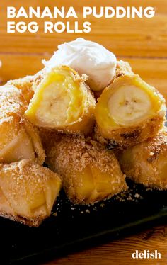 banana pudding rolls on a black plate with whipped cream and powdered sugar over them