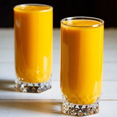 two glasses filled with orange juice on top of a table