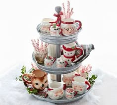 a three tiered tray with cups and mugs on top of it in the snow