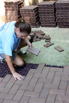 a woman is laying bricks on the ground