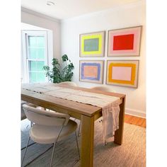 a dining room table with chairs and paintings on the wall