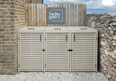 an outdoor storage unit with the bin shed sign above it and stone wall behind it