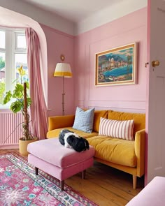 a living room with pink walls, yellow couches and rugs on the floor