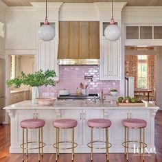 a kitchen with white cabinets and pink stools