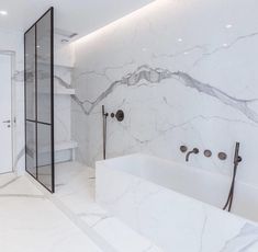 a bathroom with marble walls and flooring next to a bathtub in the corner