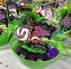 a table topped with green buckets filled with candies and candy bars covered in purple and green wrappers