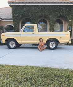 a nude woman sitting in front of a yellow truck