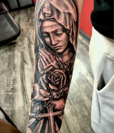 a woman with a rosary and rose tattoo on her arm