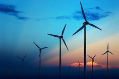 a group of windmills that are standing in the sky at sunset or dawn with clouds