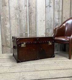 a brown leather chair sitting next to an old trunk