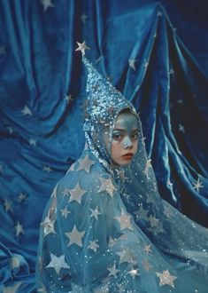 a woman with blue makeup and stars on her face is dressed in a costume that looks like a wizard's hat