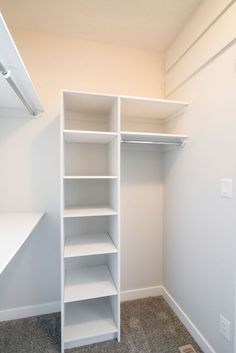 an empty white closet with shelves and shelving unit in the corner on carpeted floor