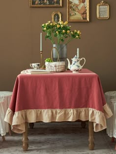 a table topped with a vase filled with flowers next to two pictures on the wall