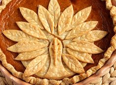 a close up of a pie with leaves on the top and bottom crust, in a woven basket