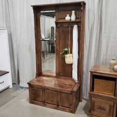 a large wooden cabinet sitting next to a mirror on top of a table in front of a white curtain