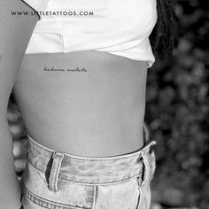 the back of a woman's stomach with tattoos on her left side, and an inscription