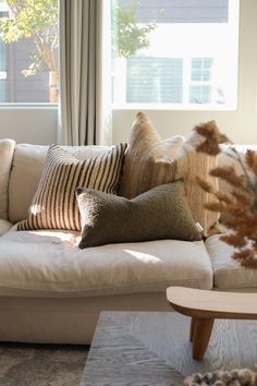 a living room filled with lots of pillows on top of a couch next to a window