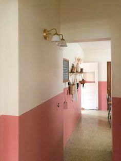 the hallway is painted pink and white with some hanging utensils on the wall