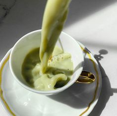 a spoon pouring green liquid into a white bowl