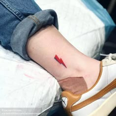 a small red arrow tattoo on the ankle