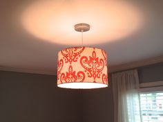 a lamp hanging from the ceiling in a room with curtains on the window sill