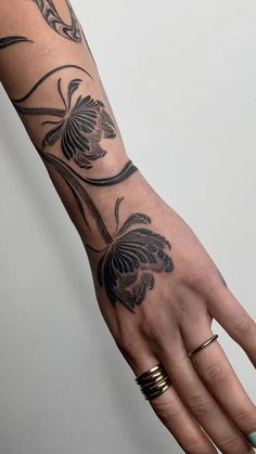 a woman's hand with a butterfly tattoo on the left wrist and two gold rings