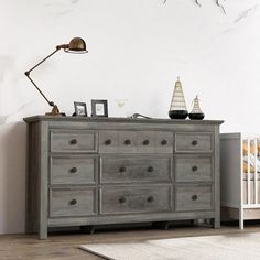 the dresser is made of wood and has two lamps on each side, along with a baby's crib