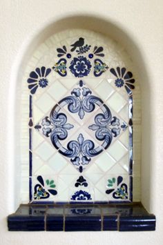 an ornate window with blue and white tiles on the outside, framed by a brick wall