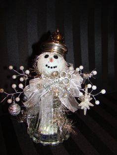 a glass snowman with a crown on it's head and some lights around his neck